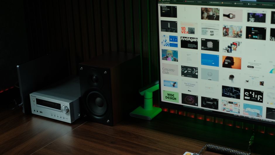 Stylish home office with computer, speaker, and audio receiver for creative design work.