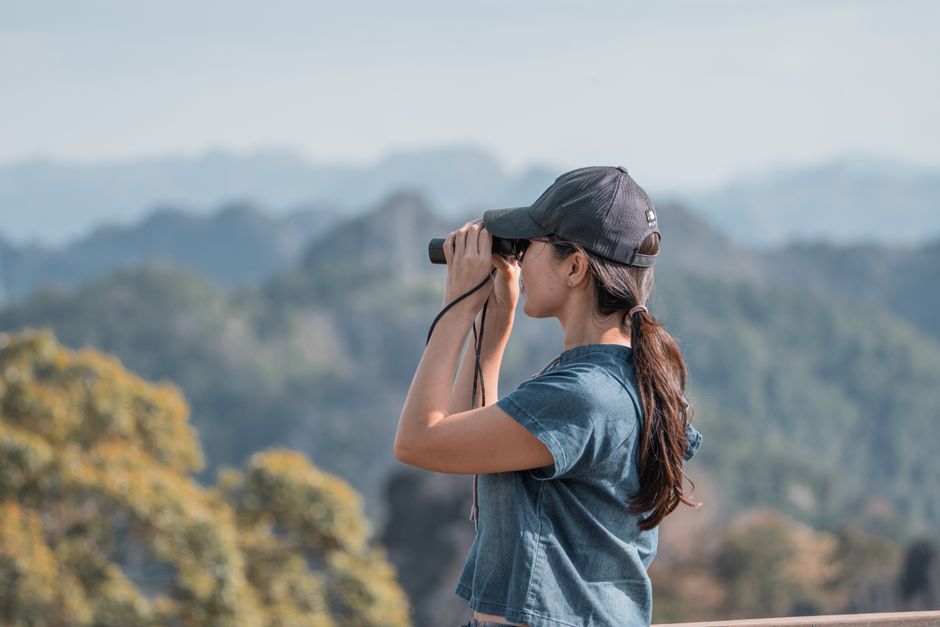 Young woman with binoculars enjoying the scenic mountain landscape in Laos.