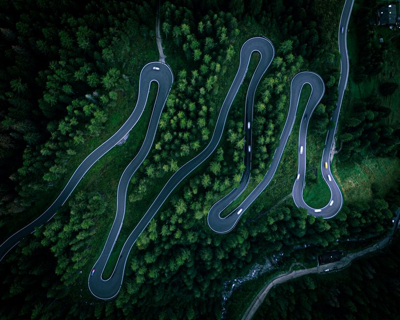 Aerial view of serpentine road through lush forest in Trentino, Italy. Perfect for travel and nature themes.