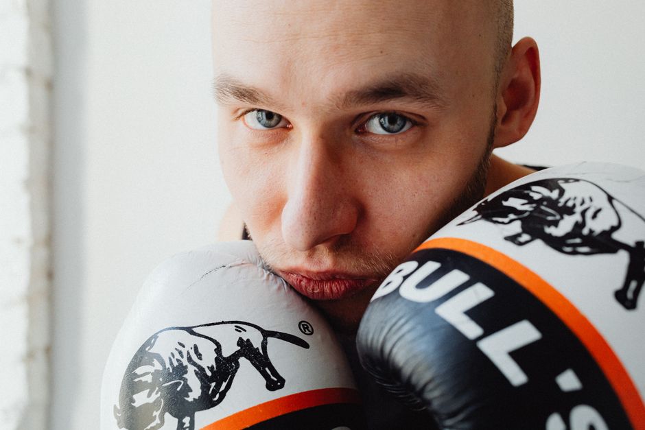 Intense close-up portrait of a male boxer with gloves, preparing for boxing indoors.