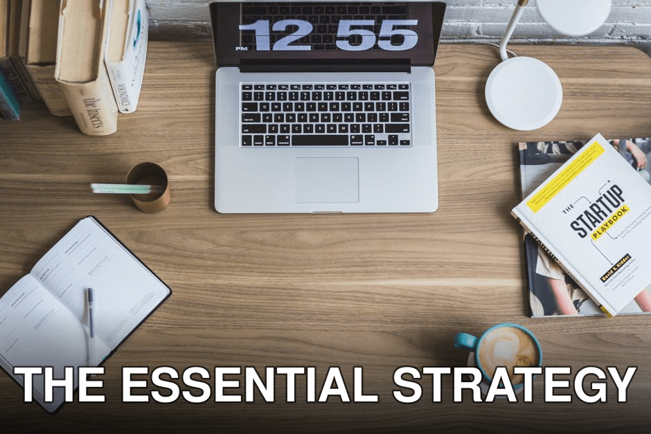 Flat lay of a modern workspace with a laptop, coffee cup, and startup books on a wooden desk.