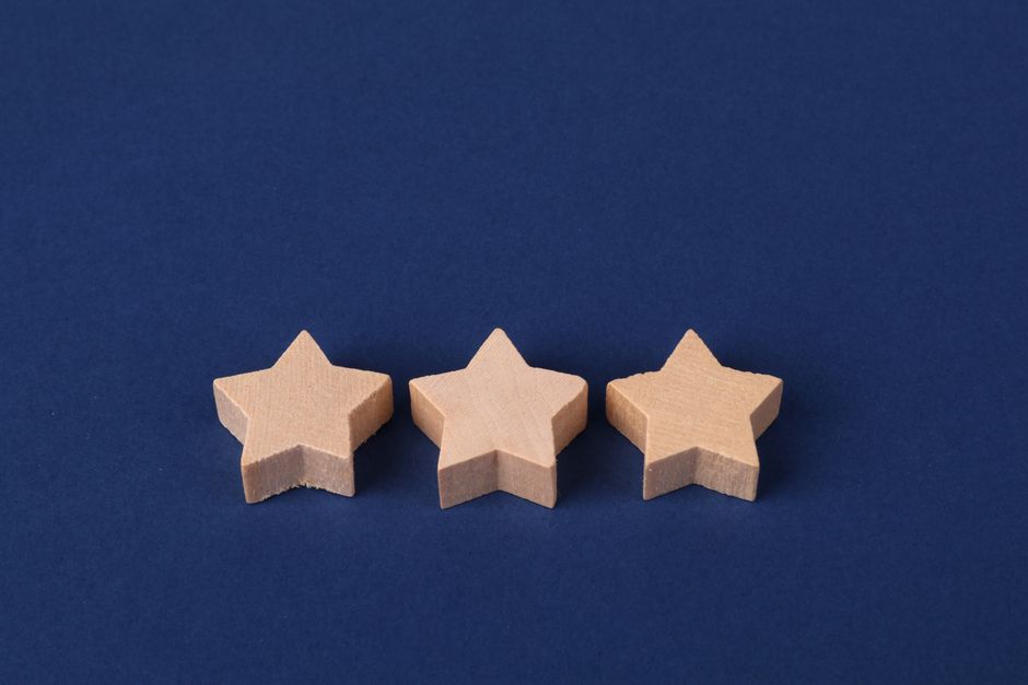 Three wooden star shapes arranged on a deep blue surface, minimalistic design.